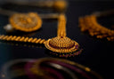 Gold necklace pendant with intricate filigree design set with red and purple gemstones in fine art gold jewelry