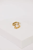 a pair of gold earrings sitting on top of a white box