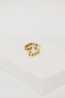 a pair of gold earrings sitting on top of a white box