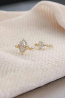 Two gold rings with marquise and round-cut stones surrounded by diamonds on cream fabric for men’s gold jewelry.