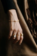 Gold chain bracelet with delicate pendant and beads complements men’s gold rings in fine gold jewelry collections.