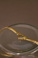 a gold necklace in a glass bowl on a table