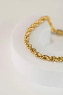 a close up of a gold bracelet on a white surface