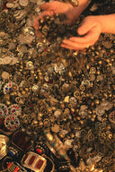 A pile of assorted metallic coins and art gold jewelry with intricate designs and colorful gemstones in lost royal jewels saga
