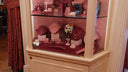 A display case featuring pink and silver art gold jewelry including necklaces and earrings revealing hidden compartments