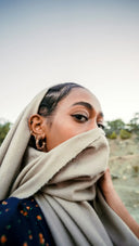 Beige woolen hijab draped over head and shoulders complementing the art gold and fine jewelry in cultural legends.