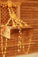 A collection of 18k gold jewelry featuring intricate fine jewelry chains and pendants displayed on a wooden surface