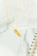 Gold-toned fine jewelry necklace with a personalized rectangular mama tag and small circular charm on a delicate chain