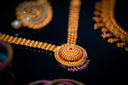 Gold necklace with intricate filigree design featuring a central red gemstone and dangling purple beads in 18k gold fine jewelry