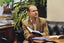 man holding book while sitting on black leather couch