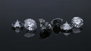 Six faceted diamonds arranged in a row on a reflective black surface