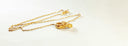 gold and silver necklace on white surface
