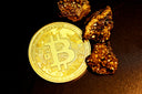 a bitcoin sitting on top of a pile of gold nuggets