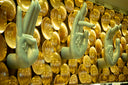 a wall of gold plates with hands and fingers on them