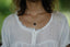a woman wearing a white shirt and a black necklace