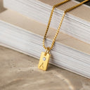 a gold necklace with a diamond on top of a stack of books