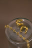 a pair of gold earrings sitting on top of a glass container