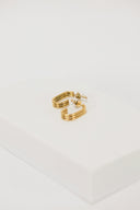 a pair of gold earrings sitting on top of a white box