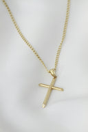 A gold cross necklace on a mannequin