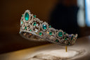 A tiara with emeralds and diamonds on a table