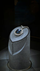 A diamond and sapphire ring on display in a glass case