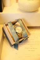 A gold watch rests inside its presentation box