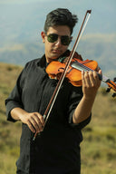 Man playing violin outdoors with mountains in background