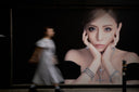 Woman walking past a large advertisement of a woman