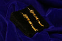 Gold dangle earrings on black velvet display