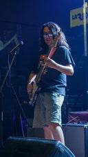 A man plays a bass guitar on stage.