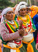 Two women in traditional colorful clothing and jewelry.
