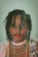 A woman with dreadlocks and layered necklaces.
