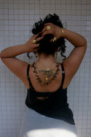 Woman with tattoo and jewelry poses against tiled wall
