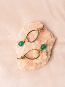 Gold earrings with green gemstones on pink stone