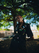 A black woman in a decorated blazer under a tree