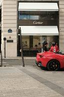 Two men stand by a red convertible outside cartier store.