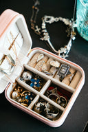 A pink jewelry box filled with necklaces and rings.