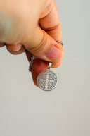 Hand holding a silver st. benedict medal necklace