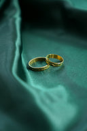 Two gold wedding rings on a green satin background