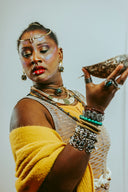 Woman in elaborate jewelry holds a seashell