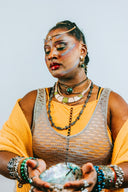 Woman with elaborate makeup and jewelry holds shell