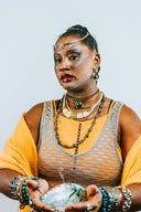 Woman with elaborate makeup and jewelry holds shell