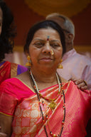 An elderly woman in a pink sari and jewelry