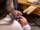 A person works on jewelry with pliers.