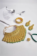 Gold jewelry set with green stones and design sketch.