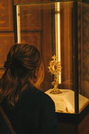 Woman observes ornate golden religious relic in display case.
