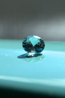 A faceted blue gemstone rests on a bright blue surface.