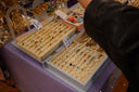 A person's hand browsing trays of rings and jewelry.