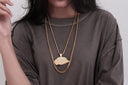 Person wearing two gold chains and a baseball cap pendant.
