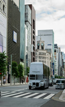 A white ferragamo double-decker bus on a city street.